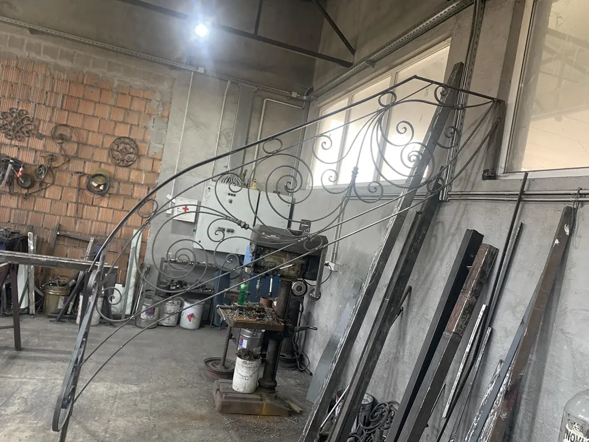 Grand ouvrage en fer forgé à volutes en cours d'assemblage en atelier, L'Art de Faire