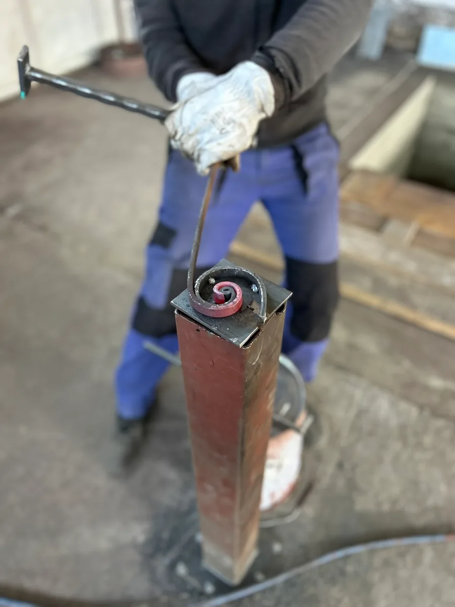 Forgeron façonnant une pièce de métal portée au rouge à la forge, atelier L'Art de Faire