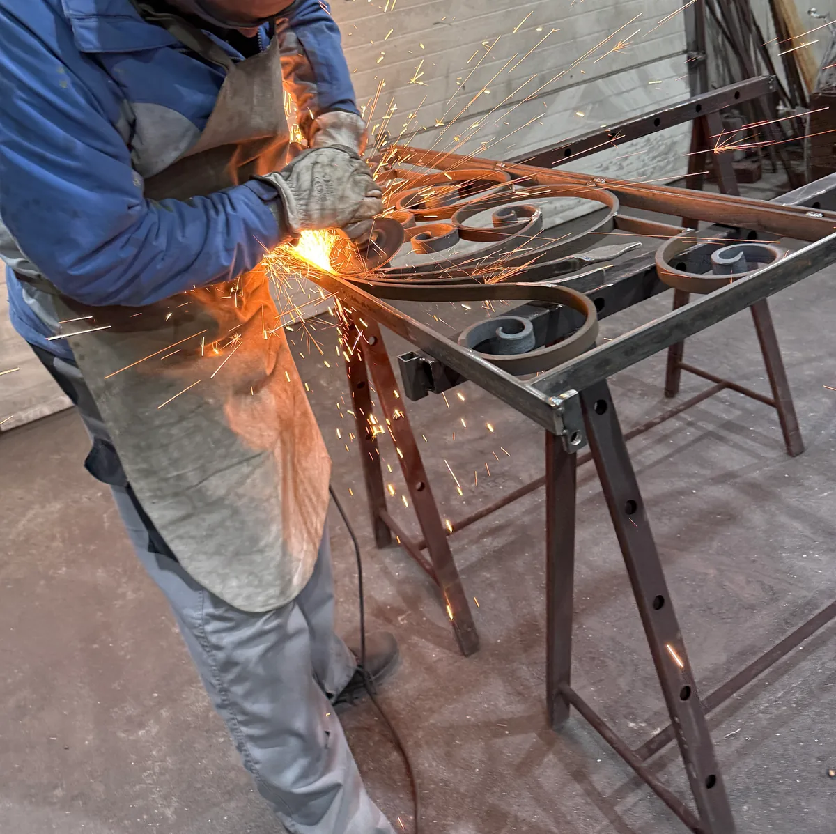 Meulage d'un ouvrage en fer forgé dans une gerbe d'étincelles, atelier L'Art de Faire