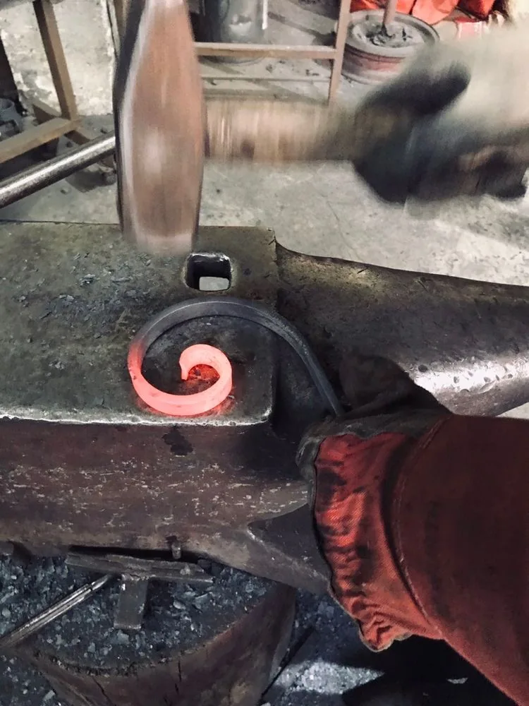 Façonnage d'une volute en fer forgé portée au rouge, atelier L'Art de Faire
