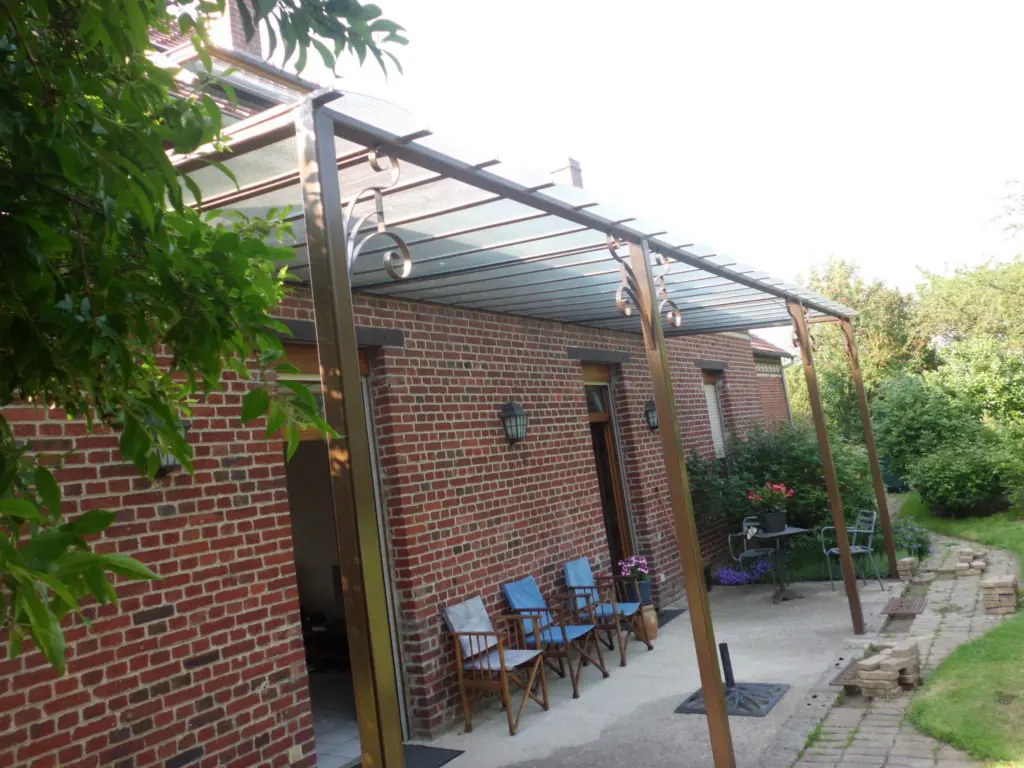 Auvent de terrasse vitré en fer forgé le long d'un mur en brique, L'Art de Faire