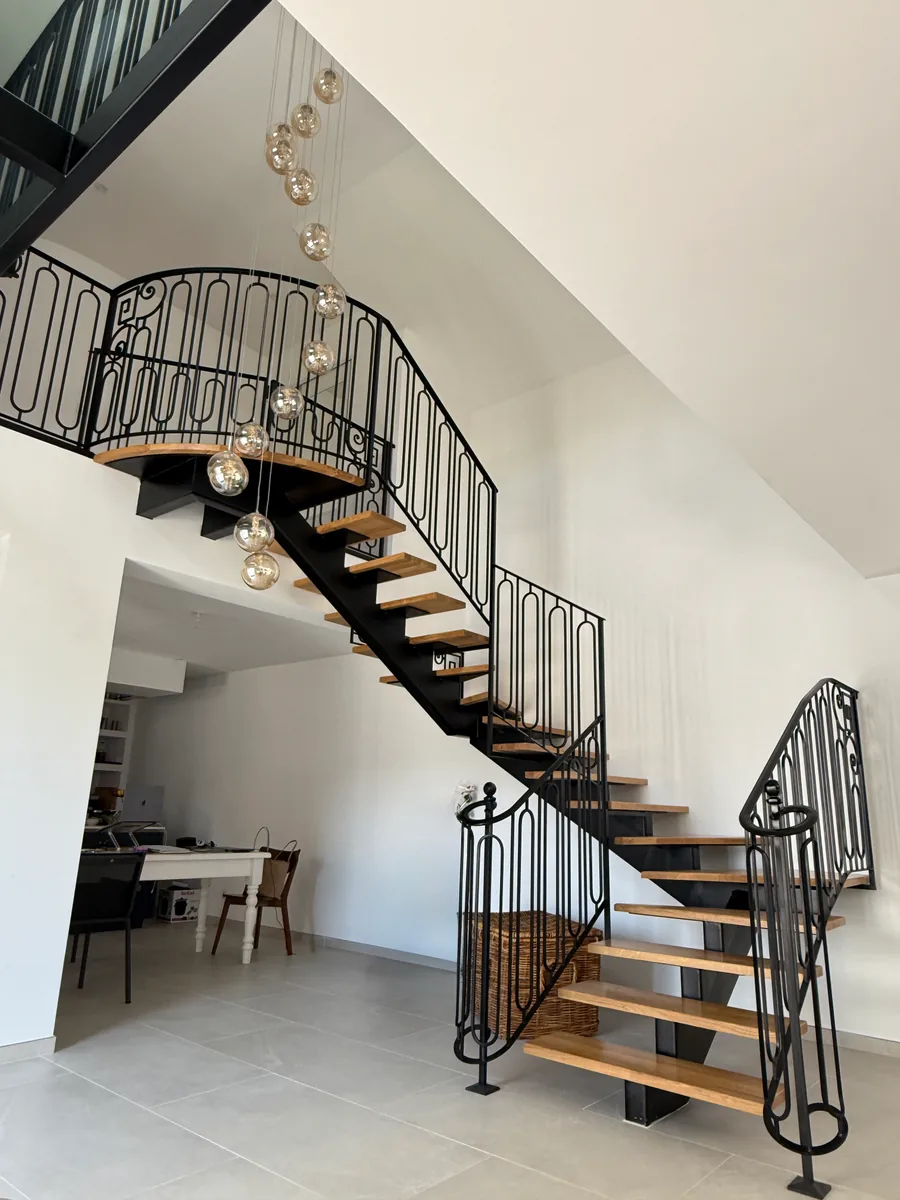 Escalier 2/4 tournant avec plateau en fer forgé, structure acier noir et marches bois, intérieur contemporain, L'Art de Faire