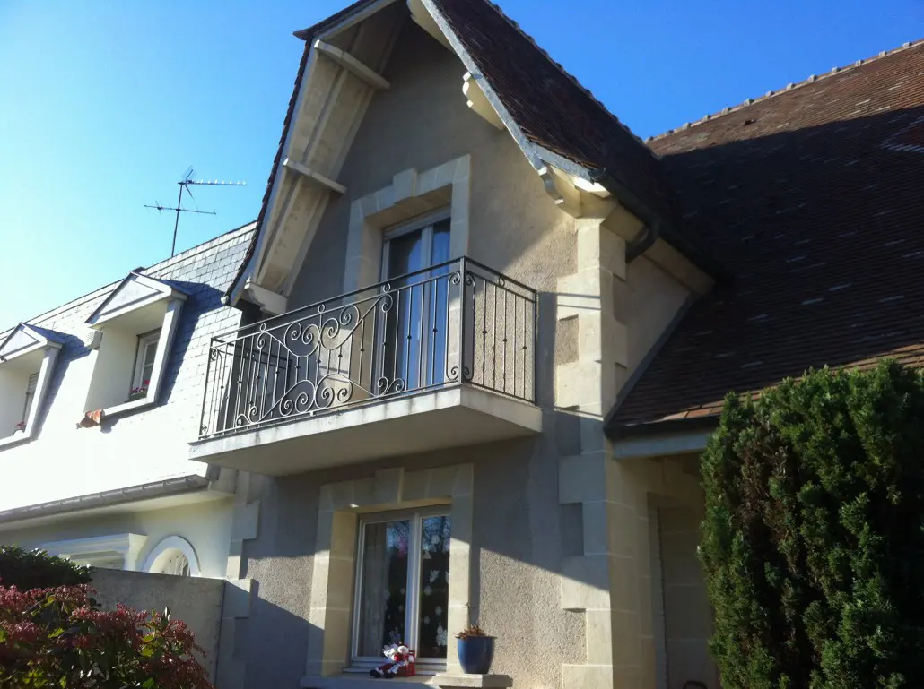 Garde-corps de balcon en fer forgé à volutes sur maison à pignon en pierre, L'Art de Faire
