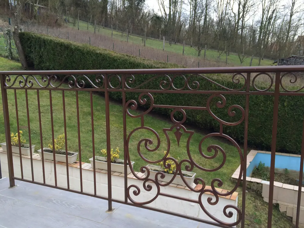 Garde-corps de terrasse extérieur brun-rouge en fer forgé à volutes et médaillon central, L'Art de Faire