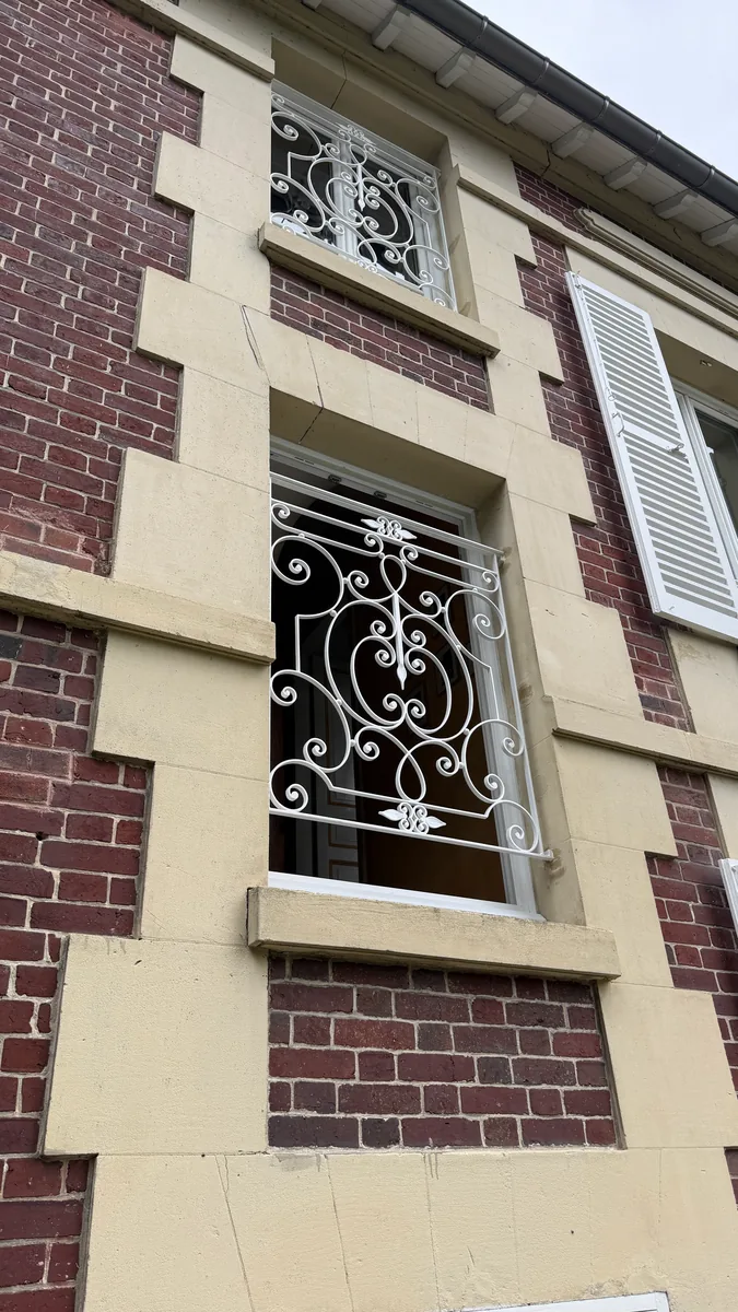 Grilles de défense en fer forgé aux fenêtres d'une maison, L'Art de Faire