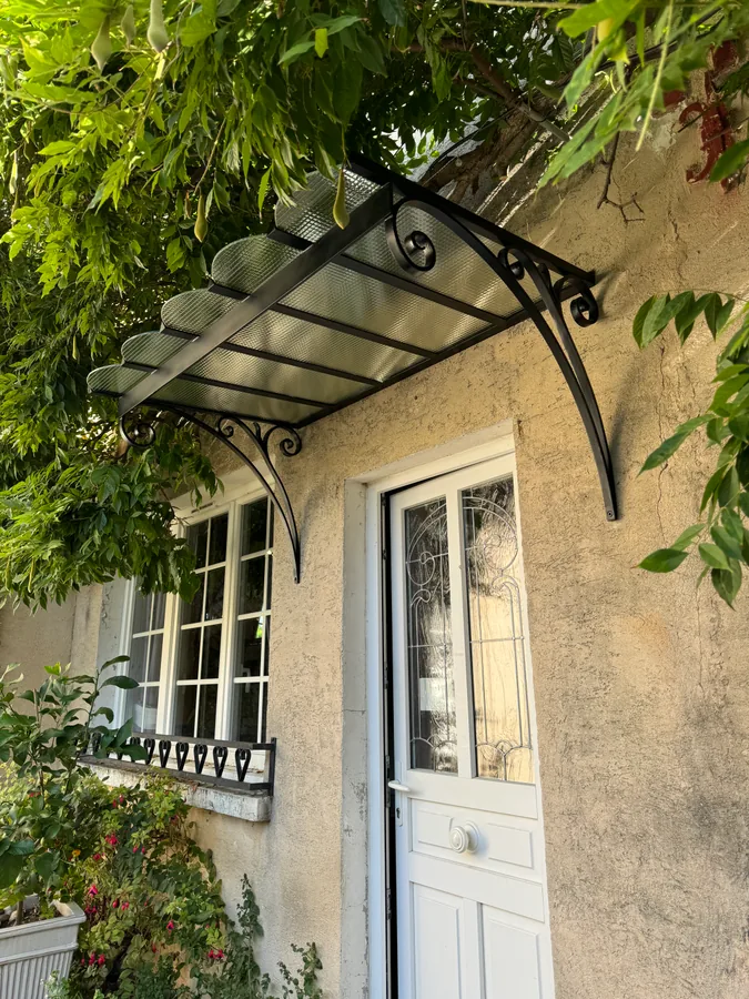 Marquise en fer forgé au-dessus d'une entrée habillée de vigne vierge, L'Art de Faire