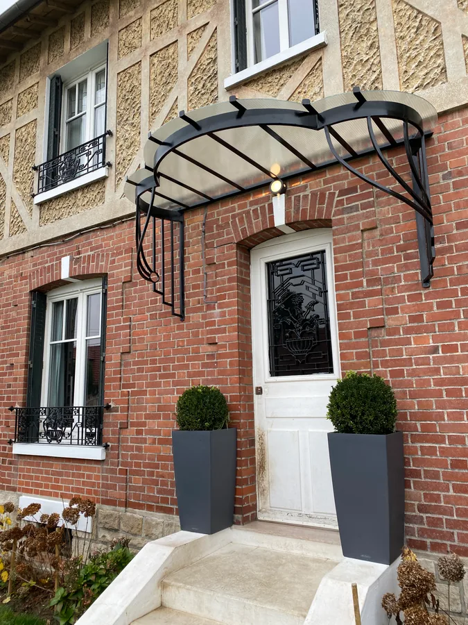 Marquise en fer forgé et verre au-dessus d'une porte d'entrée moderne, L'Art de Faire
