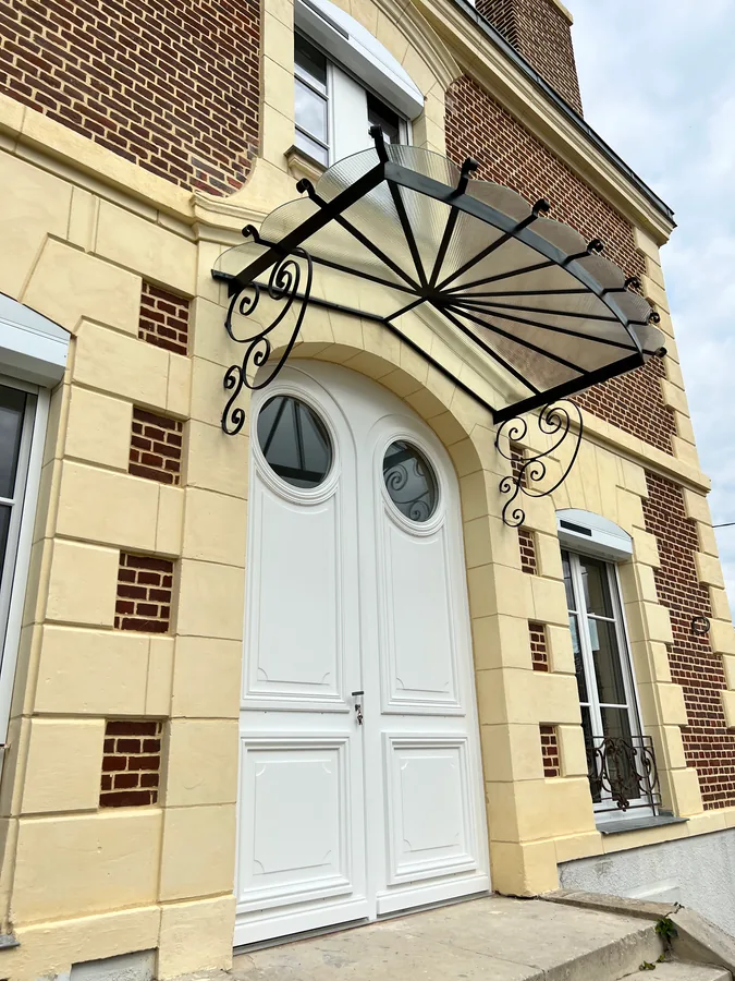 Marquise en fer forgé au-dessus d'une double porte, façade en pierre, L'Art de Faire