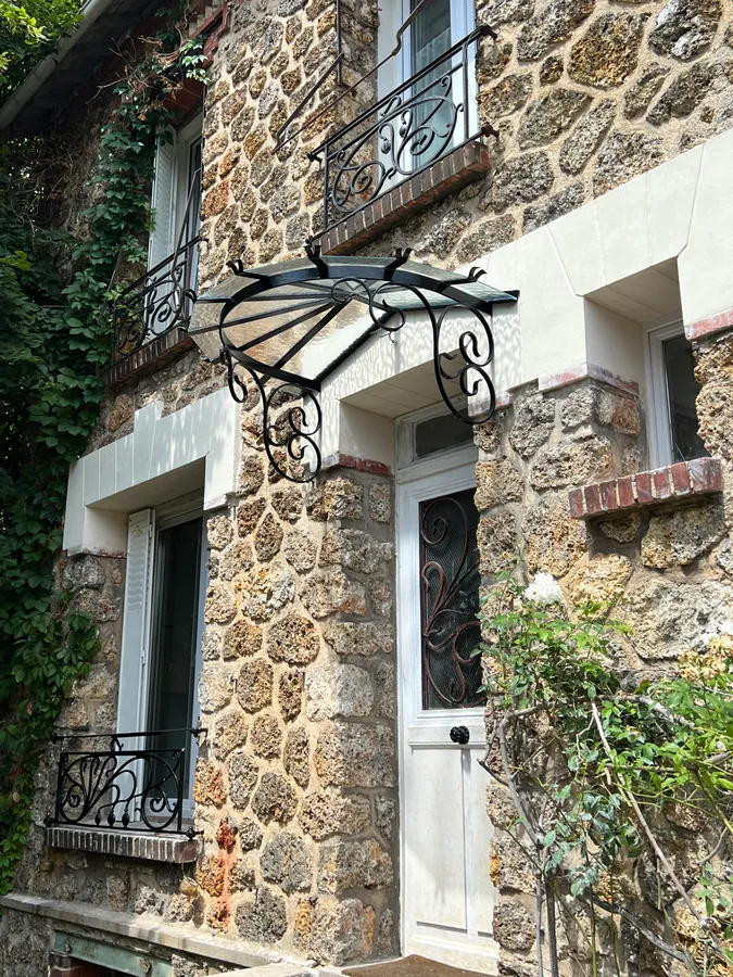 Marquise en fer forgé au-dessus d'une porte d'entrée, maison en meulière, L'Art de Faire
