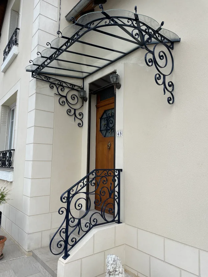 Marquise en fer forgé au-dessus d'une porte d'entrée sur façade en brique, L'Art de Faire