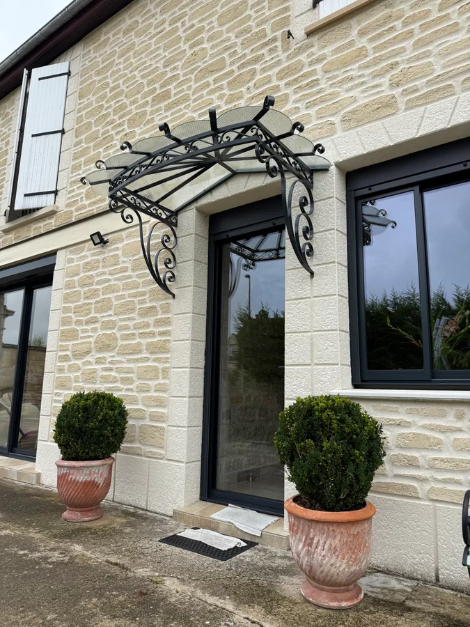 Marquise en fer forgé au-dessus d'une porte d'entrée, maison en pierre, L'Art de Faire