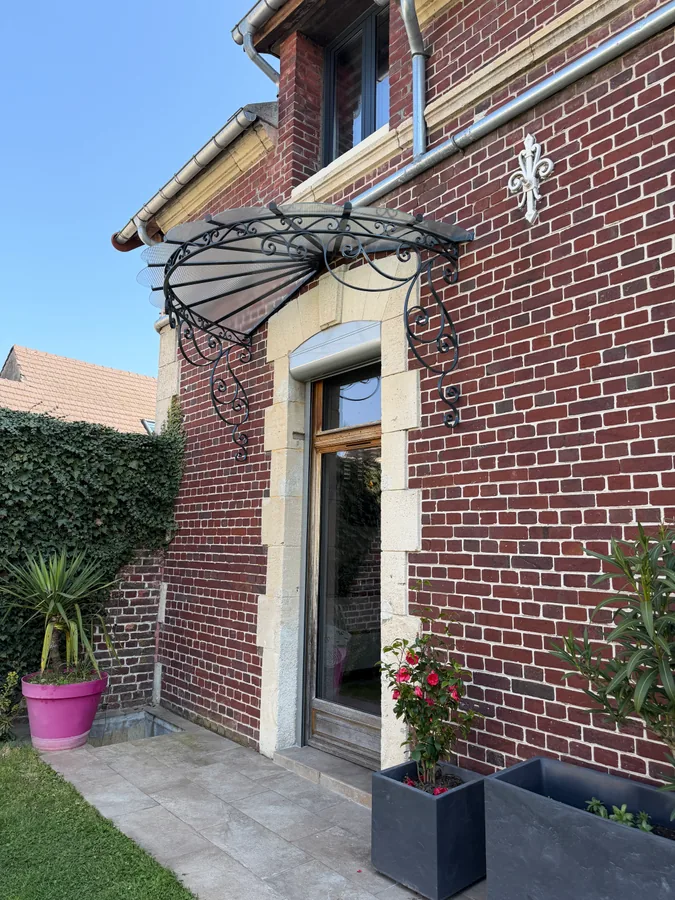 Marquise en fer forgé au-dessus d'une porte d'entrée, maison en brique, L'Art de Faire