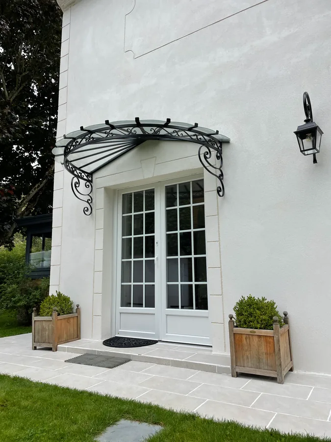 Marquise en fer forgé au-dessus d'une fenêtre, façade blanche, L'Art de Faire