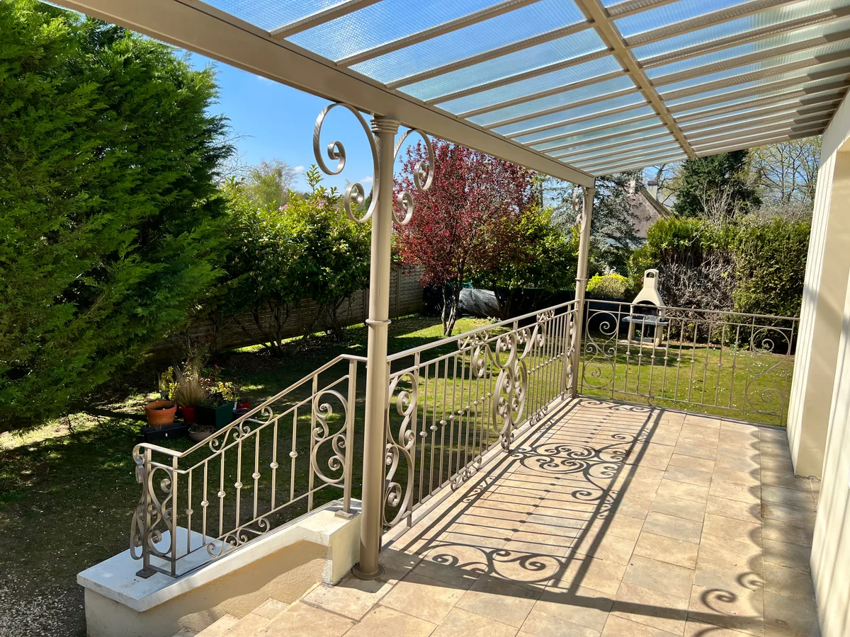 Auvent vitré sur structure en fer forgé au-dessus d'une terrasse de jardin, L'Art de Faire