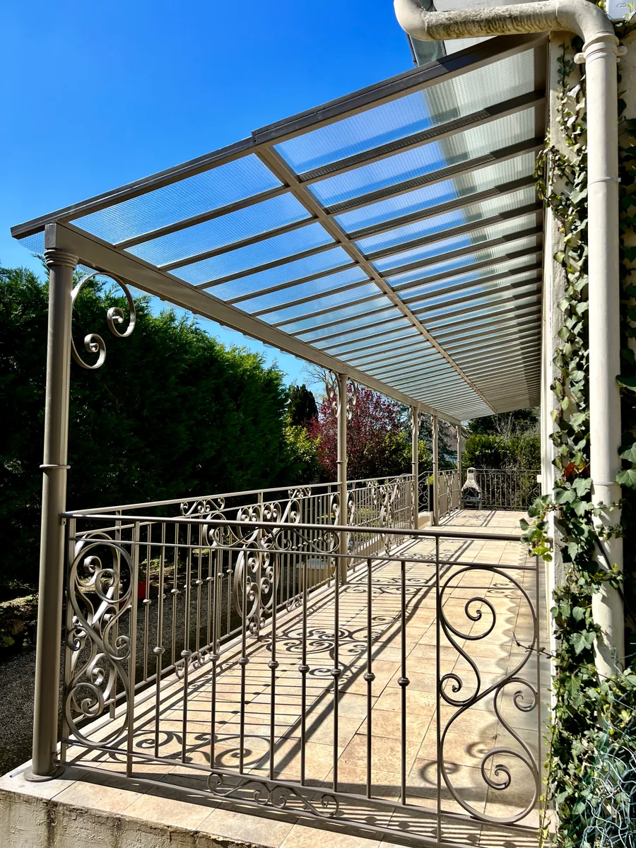 Grand auvent vitré en fer forgé au-dessus d'une terrasse avec balustrade, L'Art de Faire