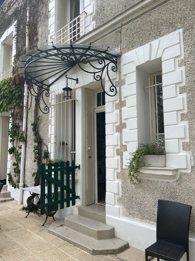 Marquise ouvragée en fer forgé au-dessus d'une porte d'entrée, maison en pierre, L'Art de Faire