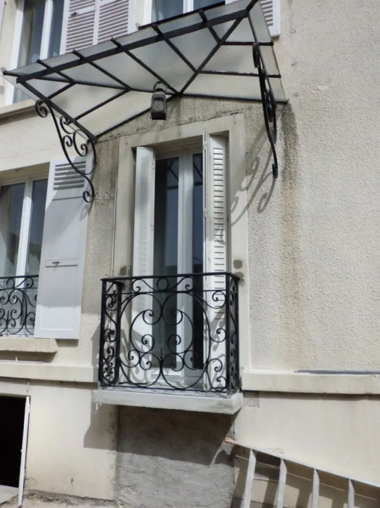 Marquise en fer forgé au-dessus d'une fenêtre avec balconnet assorti, L'Art de Faire