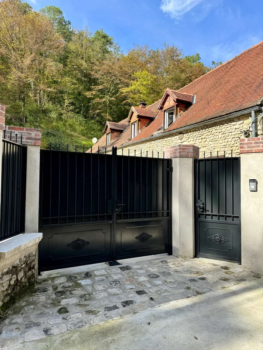 Portail et clôture en fer forgé noir le long d'une allée, L'Art de Faire