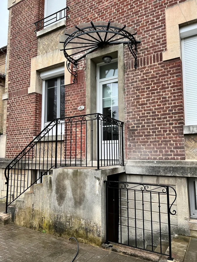 Garde-corps de balcon cintré en fer forgé sur une façade en brique, L'Art de Faire