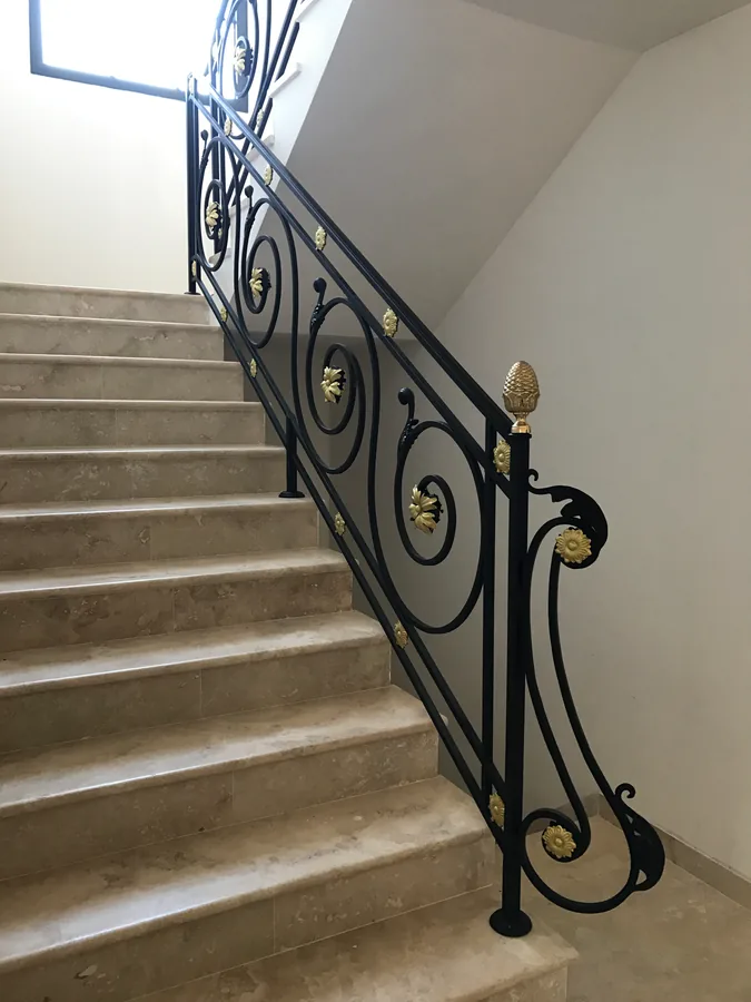Rampe en fer forgé à volutes le long d'un escalier en pierre, L'Art de Faire