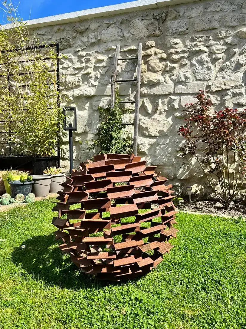 Sculpture sphère en acier patiné dans un jardin, réalisation L'Art de Faire