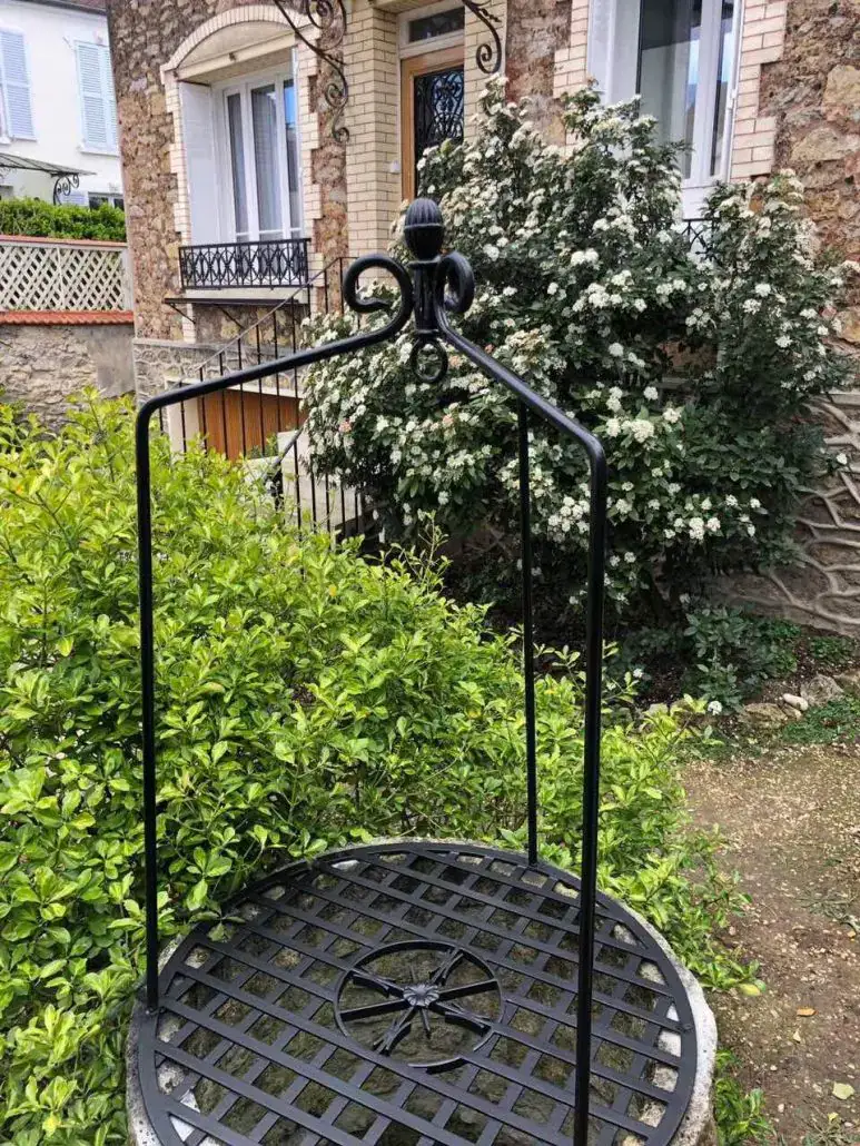 Structure de puits décoratif en fer forgé dans un jardin, L'Art de Faire